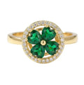 Gold ring with green gemstone and diamond accents on a white background