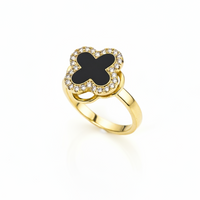 Gold ring with a black clover-shaped center on a white background