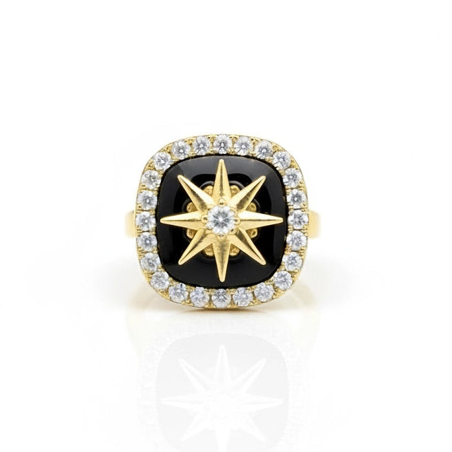 Gold ring with black gemstone and star design on a white background